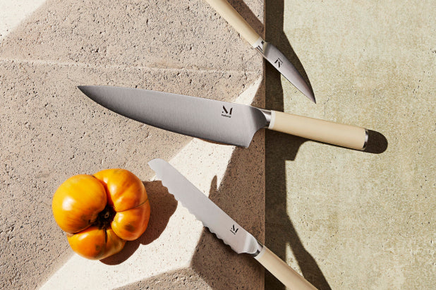 Chef's knife on wooden cutting board with vegetables